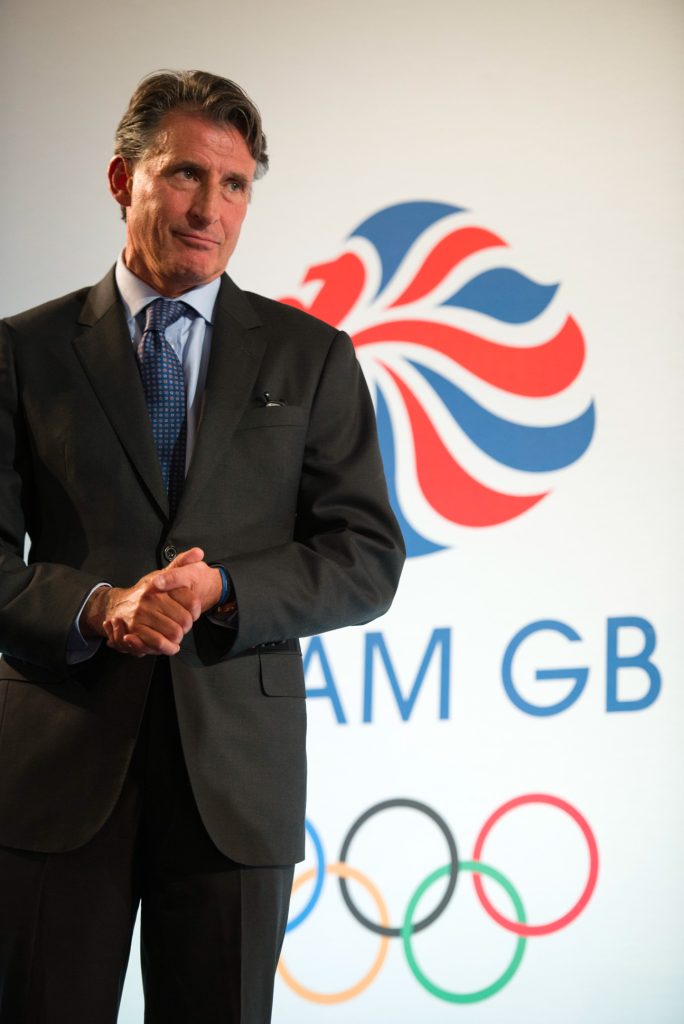Sebastien Coe in a dark suit stands in front of a Team GB logo, featuring a red, white, and blue lions head and the Olympic rings, against a white background. Event photographer Manchester